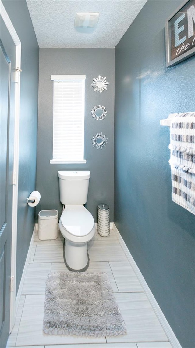 bathroom with toilet, baseboards, and a textured ceiling