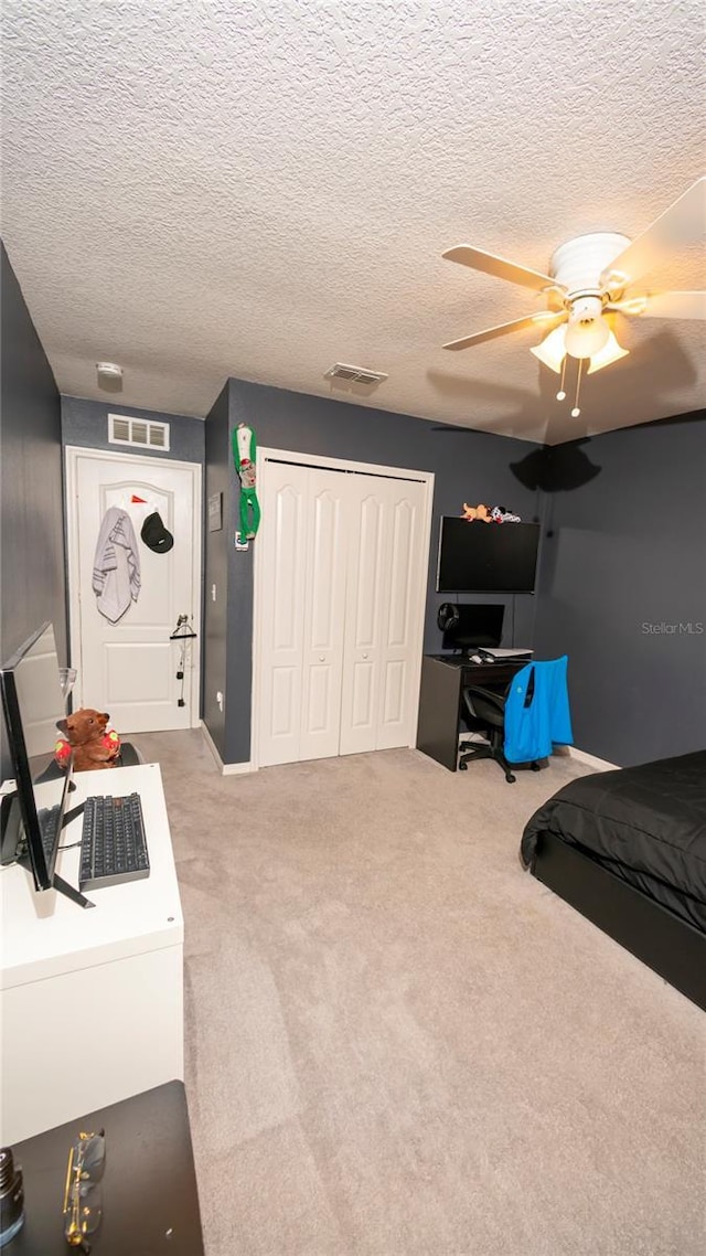 bedroom with carpet, visible vents, a closet, and a textured ceiling