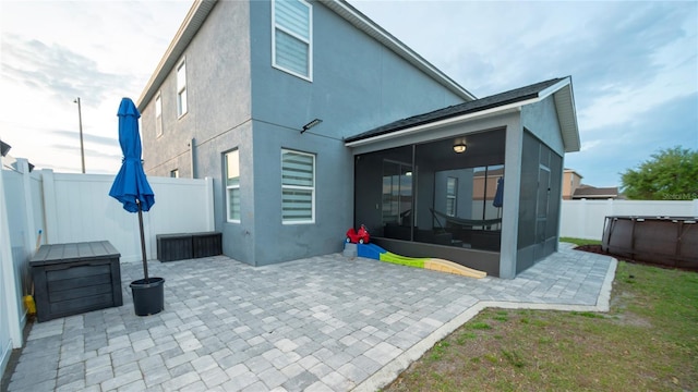 rear view of house featuring a fenced in pool, a fenced backyard, a sunroom, stucco siding, and a patio area