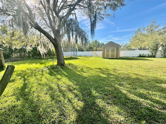 view of yard featuring an outbuilding, a trampoline, a fenced backyard, and a shed