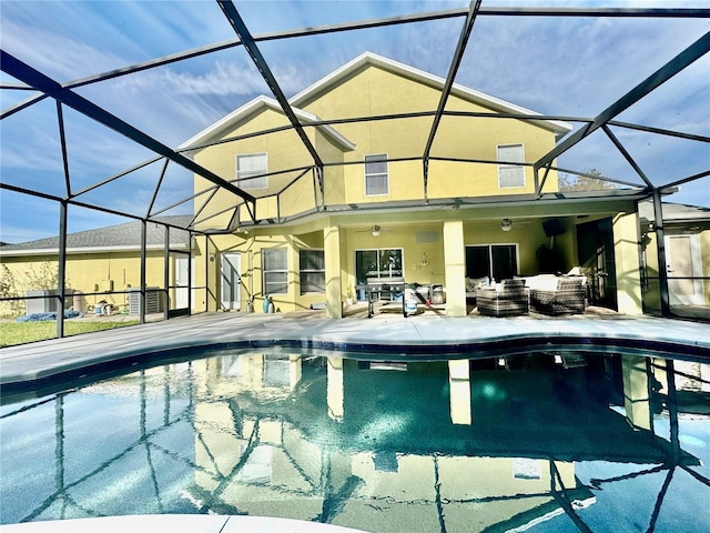 outdoor pool with glass enclosure, ceiling fan, and a patio area