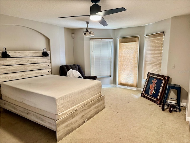 carpeted bedroom featuring baseboards, a textured ceiling, and a ceiling fan