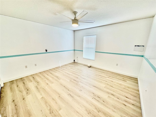 empty room with ceiling fan, wood finished floors, baseboards, and a textured ceiling