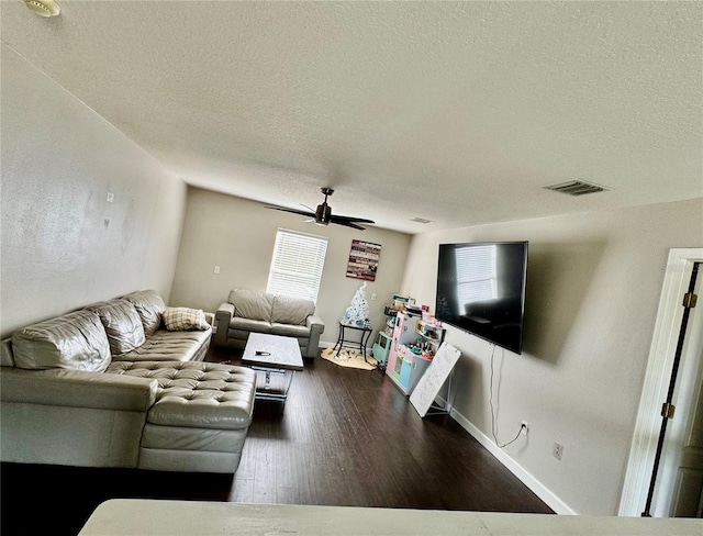 living area featuring visible vents, a textured ceiling, a ceiling fan, and wood finished floors