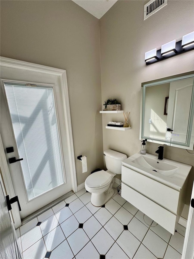 half bath featuring visible vents, toilet, vanity, and baseboards