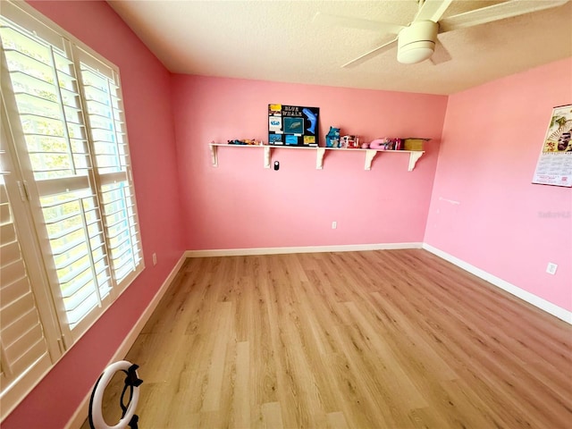 spare room featuring ceiling fan, a textured ceiling, light wood-style floors, and baseboards