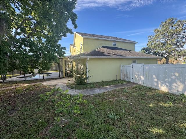 view of side of home featuring a fenced in pool, fence, stucco siding, a yard, and a patio area