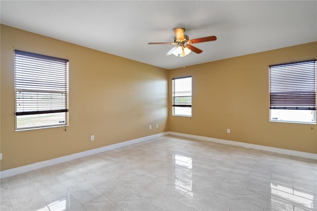 spare room featuring a ceiling fan and baseboards