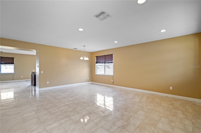 empty room featuring a chandelier, recessed lighting, visible vents, and baseboards