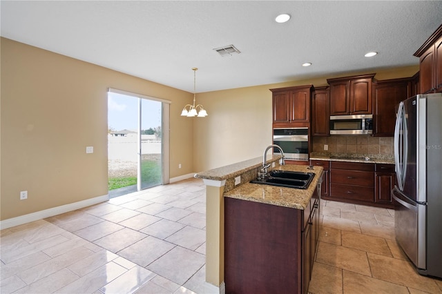 kitchen featuring a sink, visible vents, appliances with stainless steel finishes, backsplash, and an island with sink