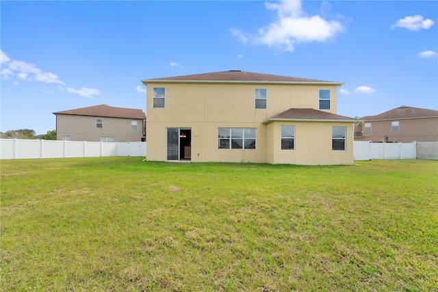 rear view of property with a lawn, a fenced backyard, and stucco siding