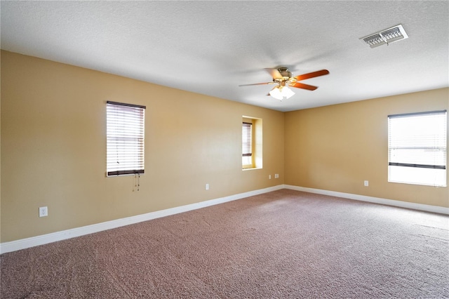 carpeted spare room with baseboards, a textured ceiling, visible vents, and a ceiling fan