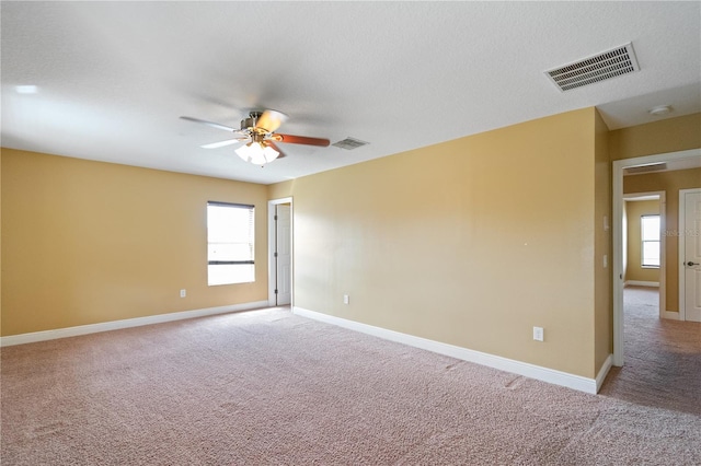 unfurnished room featuring light carpet, ceiling fan, visible vents, and baseboards