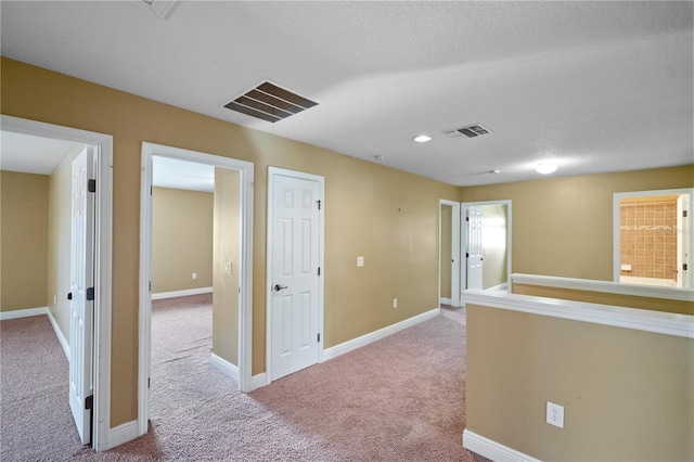 hallway with carpet flooring, visible vents, and baseboards