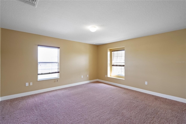 carpeted empty room featuring baseboards, visible vents, and a textured ceiling