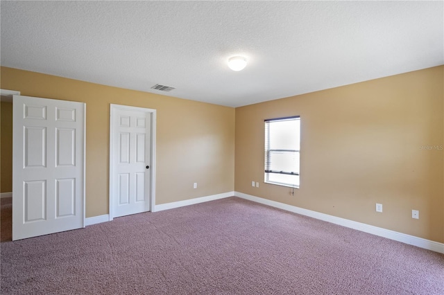 unfurnished bedroom with carpet, visible vents, baseboards, and a textured ceiling