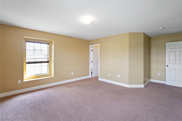 carpeted spare room featuring visible vents, a textured ceiling, and baseboards