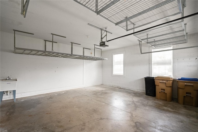 garage featuring concrete block wall, a sink, and a garage door opener