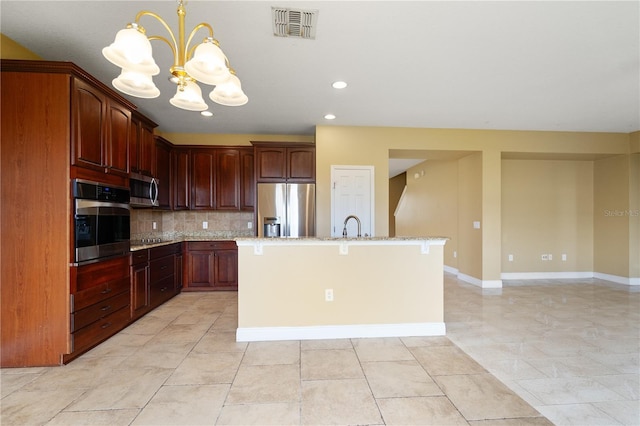 kitchen featuring visible vents, baseboards, appliances with stainless steel finishes, backsplash, and an island with sink