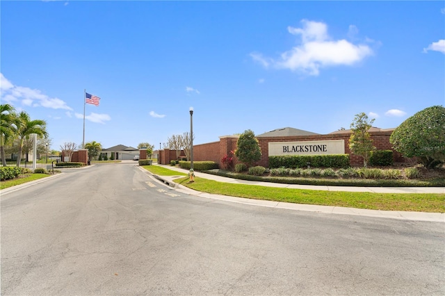 view of street with sidewalks, street lighting, a gated entry, and curbs