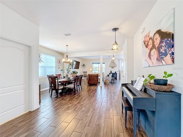 dining room featuring visible vents, wood finish floors, a wealth of natural light, and an inviting chandelier