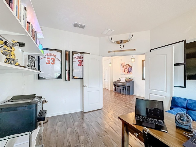 interior space with baseboards, visible vents, and wood finished floors