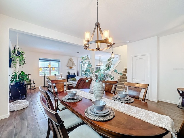 dining space with dark wood-style floors, baseboards, stairs, and a chandelier