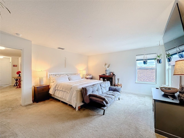 bedroom with light carpet, baseboards, visible vents, and a textured ceiling