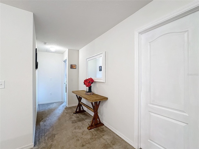 corridor with baseboards and carpet flooring