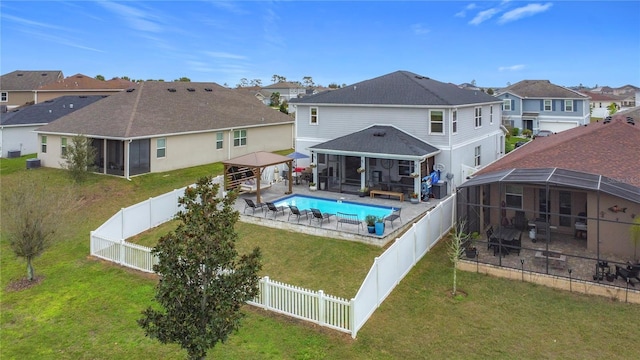 back of house featuring a fenced backyard, a sunroom, a gazebo, a lawn, and a residential view