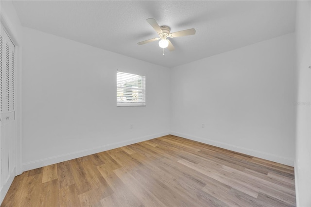 spare room featuring a textured ceiling, a ceiling fan, light wood-style flooring, and baseboards