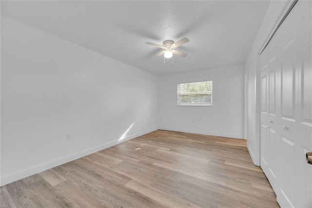 unfurnished room with light wood-type flooring, a ceiling fan, and baseboards