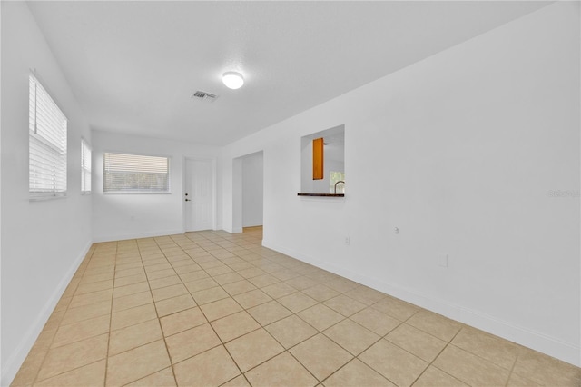 empty room featuring light tile patterned flooring, visible vents, and baseboards