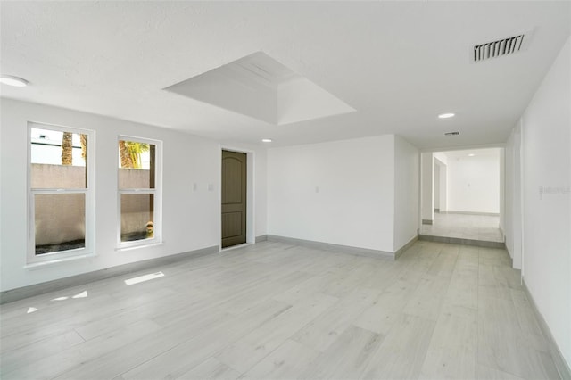 spare room featuring light wood-style floors, visible vents, and baseboards