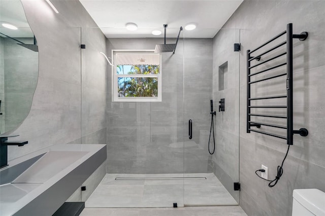 bathroom with radiator, a stall shower, toilet, and tile walls