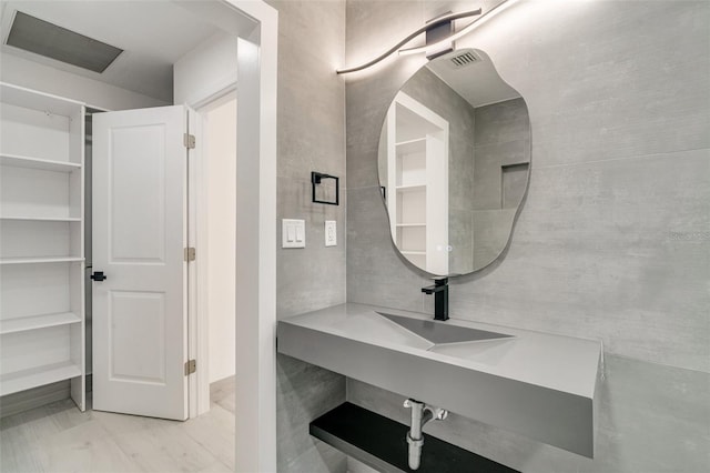 bathroom featuring tile walls, visible vents, and a sink