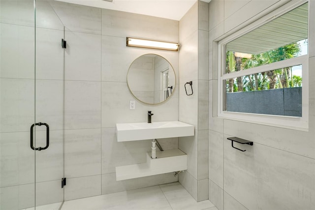 bathroom with a stall shower, tile walls, and a sink