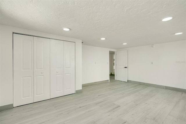 interior space featuring a textured ceiling, recessed lighting, baseboards, a closet, and light wood-type flooring