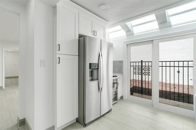 kitchen featuring light wood-type flooring, stainless steel fridge, white cabinets, and beverage cooler