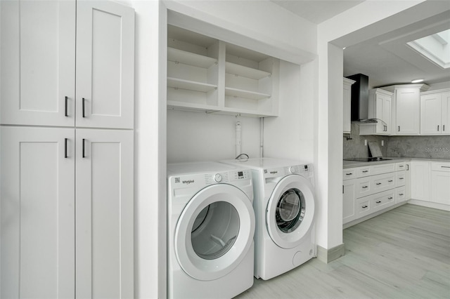 clothes washing area with light wood finished floors, laundry area, and washer and dryer