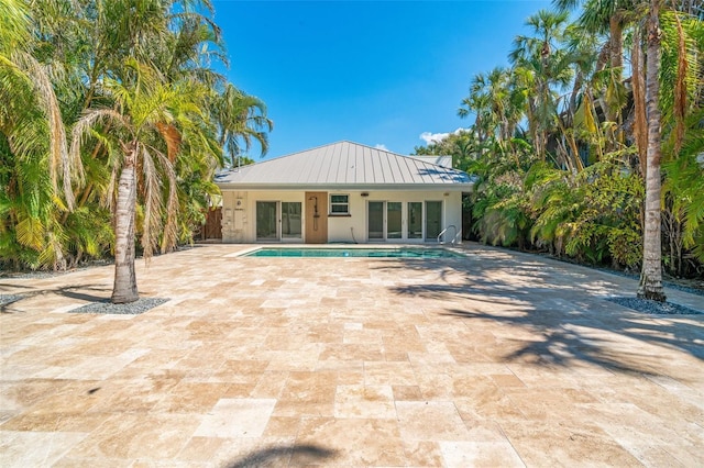 back of property with metal roof, french doors, an outdoor pool, a standing seam roof, and stucco siding