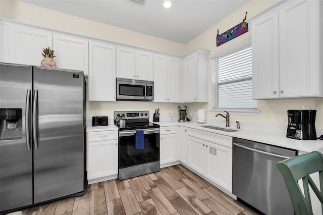 kitchen featuring white cabinetry, appliances with stainless steel finishes, light countertops, and a sink