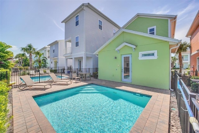 back of property with a fenced in pool, stucco siding, a patio, and fence