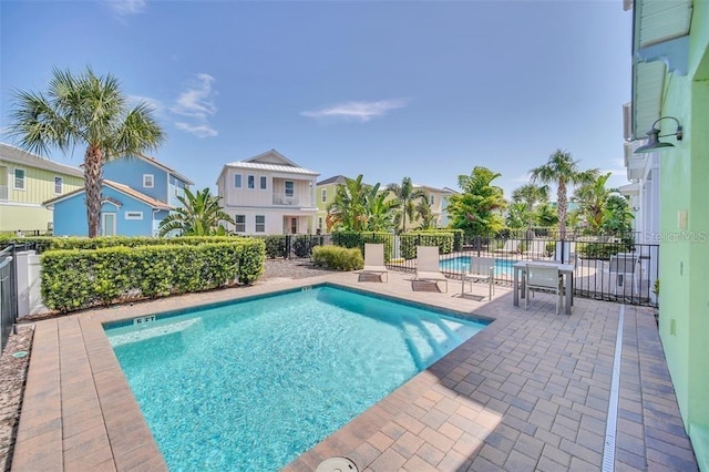 pool with a patio area, a residential view, and fence