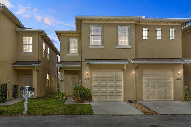 multi unit property featuring a garage, driveway, and stucco siding