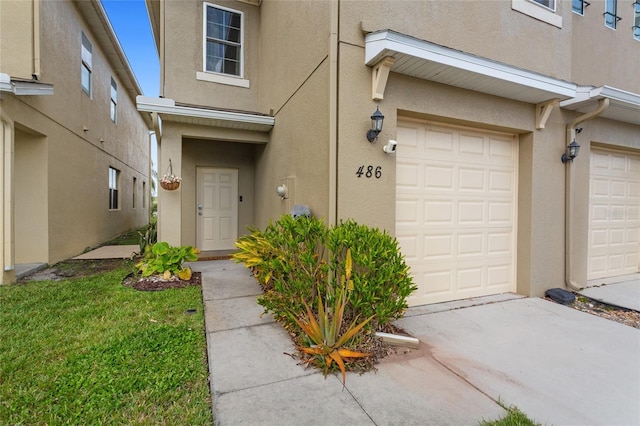 doorway to property with a garage and stucco siding