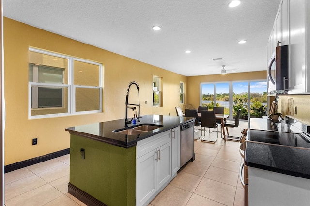 kitchen with light tile patterned floors, stainless steel appliances, a sink, and white cabinetry