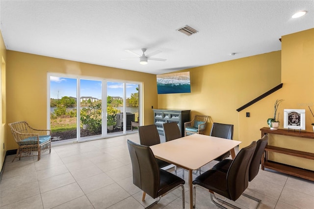 dining space featuring a textured ceiling, visible vents, a ceiling fan, and light tile patterned flooring