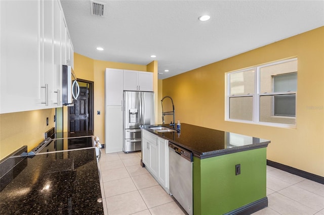 kitchen with a sink, visible vents, white cabinets, appliances with stainless steel finishes, and dark stone countertops