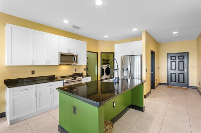 kitchen with visible vents, white cabinets, appliances with stainless steel finishes, washer and dryer, and a sink